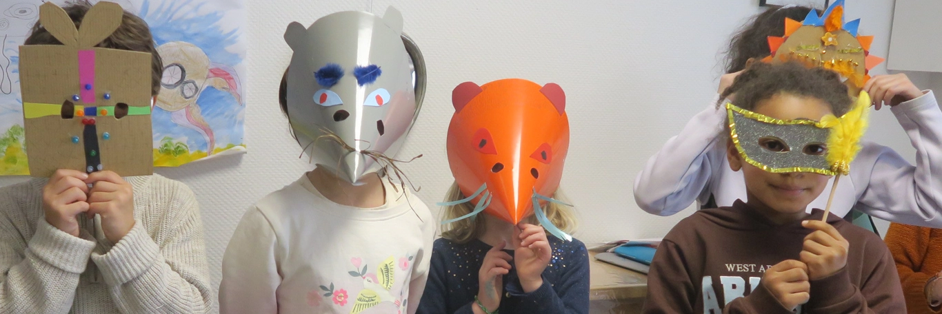 4 ou 5 enfants regardent la caméra en portant les masques qu'ils ont réalisés