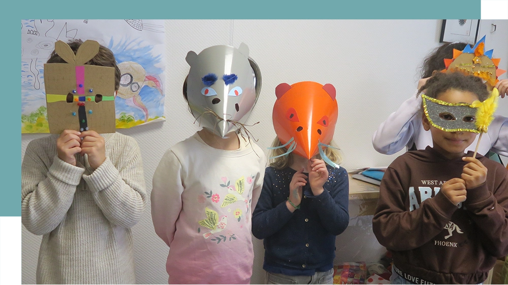 4 ou 5 enfants regardent la caméra en portant les masques qu'ils ont réalisés