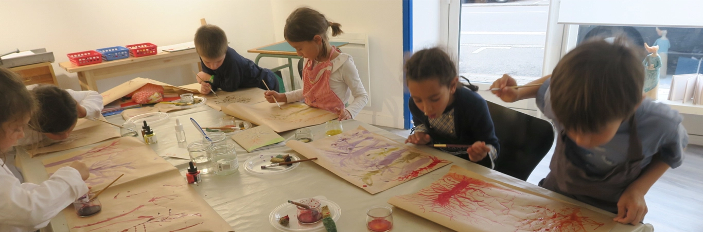 Des enfants peignent et dessinent en cours d'arts plastiques